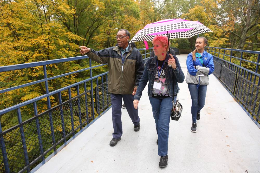 Two alumni from the class of '68 and a student walk on the Little Mac Bridge.